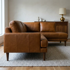 Brown leather sectional sofa in a living room setting with a lamp and decorative items on a side table.