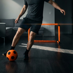 Man playing with a soccer ball in a dimly lit room with a small goalpost.