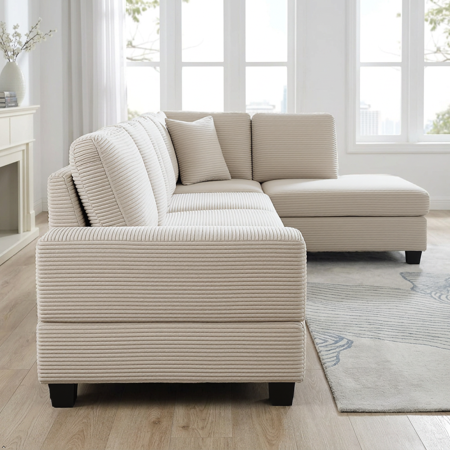 Beige sectional sofa in a living room with large windows and a rug.