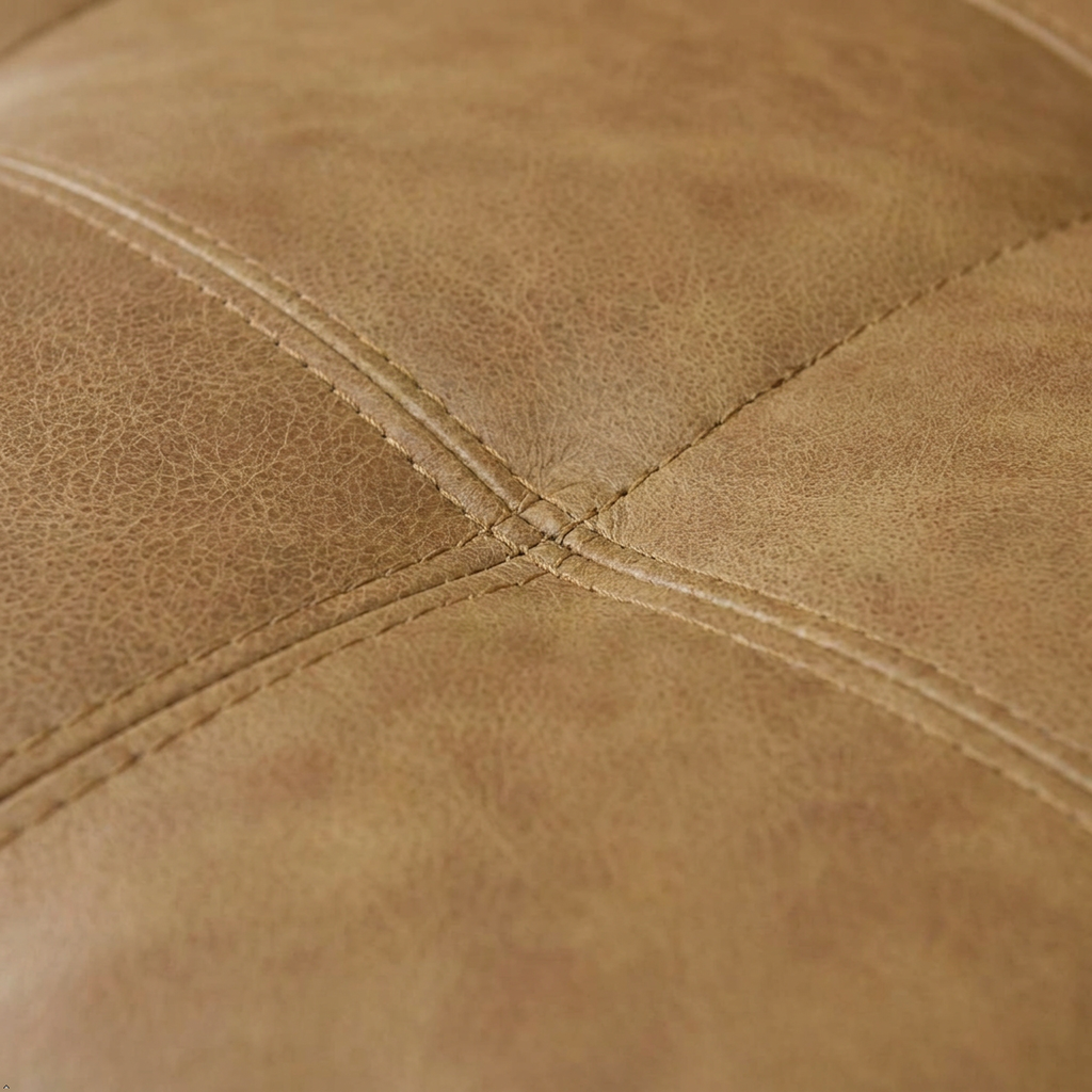 Close-up of a tan leather or faux leather upholstered surface with visible grain texture and stitched panel seams.